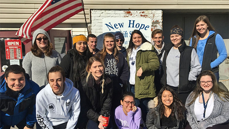 Group of students posing under flag at New Hope Shelter