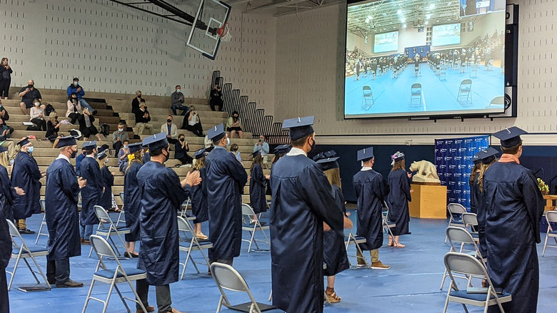Students in blue regalia clapping during ceremony 
