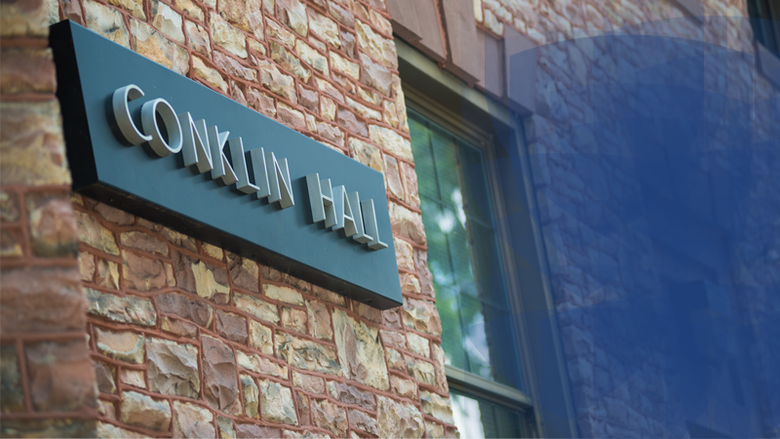 Conklin Hall with sign and blue shield graphic 