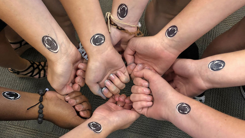 Photo of seven different hands with fake Penn State tattoos on their wrists