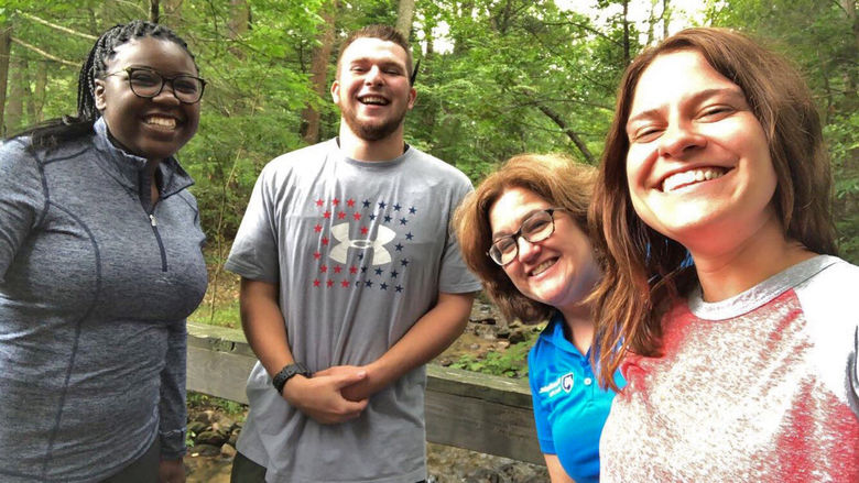 Several students take selfie with staff member in woods