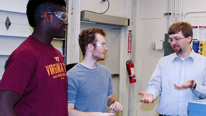 Penn State professor Jacob Moore talks to two students in a lab.