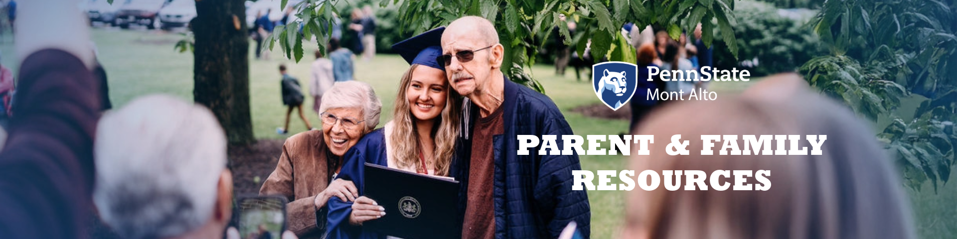 Graduate holding their diploma. Smiling for a photo with two family members.