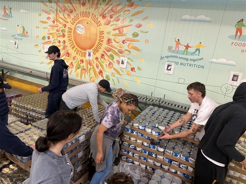 A group of students work together in a food bank to pack boxes for families
