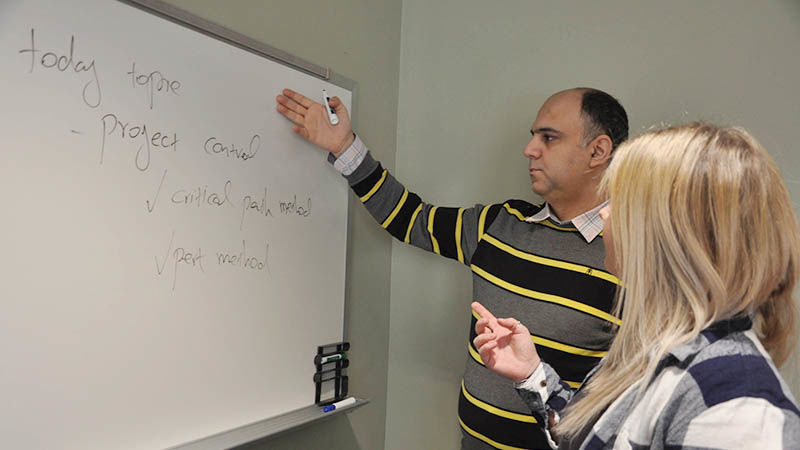 An instructor and student work together in the classroom at a whiteboard