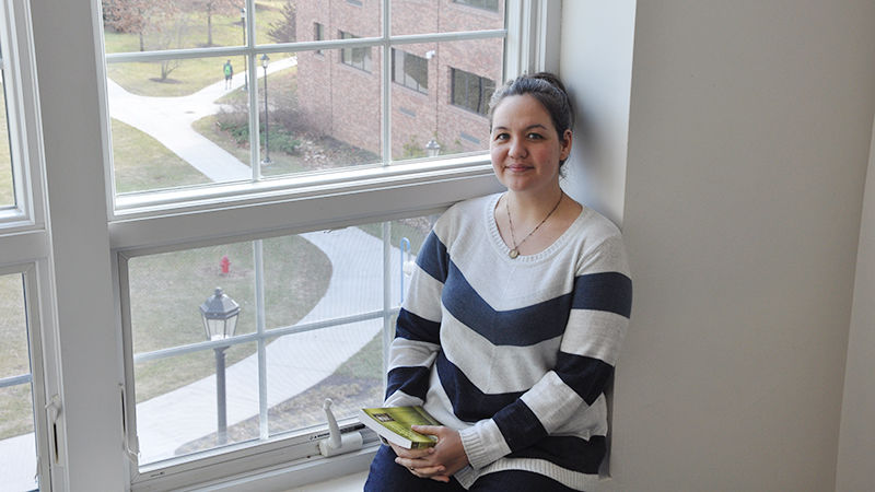 Female student sits in third story window overlooking quad