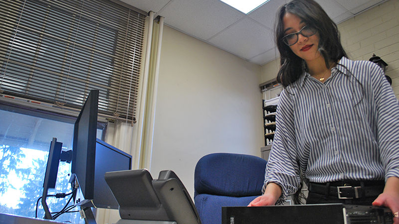 IST Emily Lautenbach fixes a computer