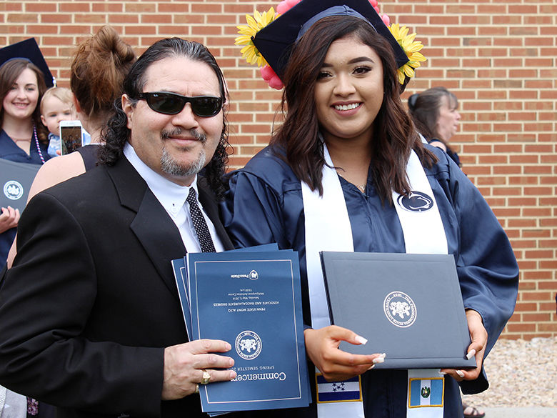 Young female graduate poses with her father at graduation