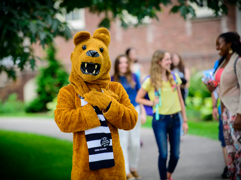 Lion Mascot stands while students walk behind