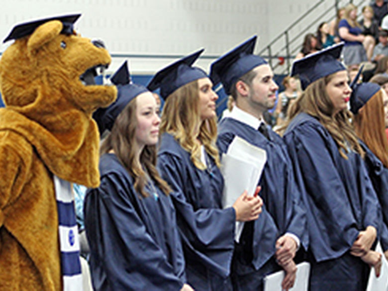Students at Commencement stand at attention with Nittany Lion