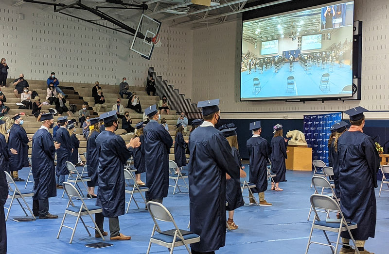 Students in blue regalia clapping during ceremony 
