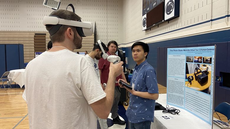 A student wears a virtual reality headset while another student looks on.