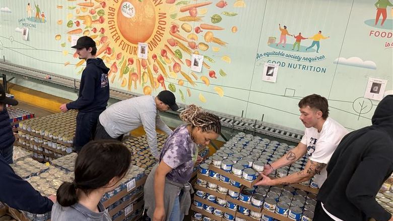 A group of students work together in a food bank to pack boxes for families