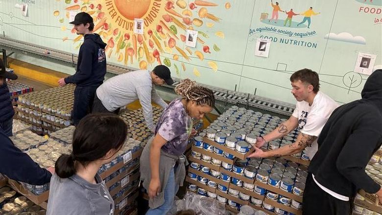 A group of students work together in a food bank to pack boxes for families