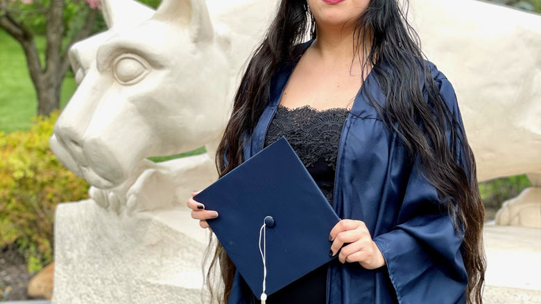 female graduate standing by lion shrine 
