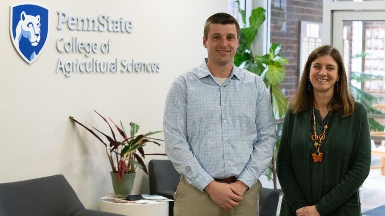 Two people stand in front of a wall that reads "Penn State College of Agricultural Sciences"