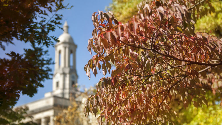 Old Main bell tower with autumn leaves in foreground