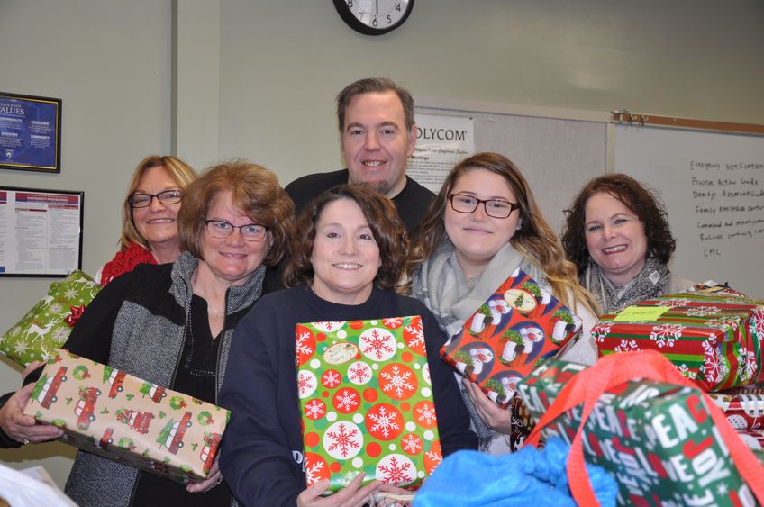 Staff members gather for a photo with wrapped gifts