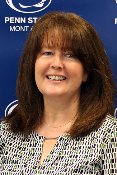 Woman with brown hair in front of blue Penn State background 